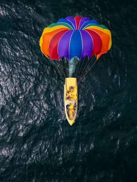 stock image Drone video of a colorful parasail soaring over the open ocean, towed by a speedboat below. The aerial view captures the thrill and freedom of parasailing against a vast, serene seascape.