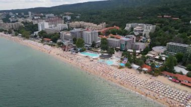 Deniz kenarında güneşli bir günün tadını çıkaran şemsiyelerle dolu güzel bir sahil manzarası. Yaz tatillerini, sahil tatil beldelerini ve seyahat deneyimlerini desteklemek için ideal. Altın kumlar