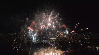 Muhteşem havai fişekler, gece gökyüzünü canlı bir şehrin rıhtımında aydınlatıyor, suyun altında yansımalar parıldıyor. Kutlamalar ve şenlik için mükemmel..