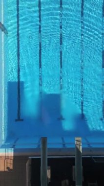 Dalış platformları olan boş bir yüzme havuzunun havadan görünüşü, berrak mavi su ve sakin çevreyi gösteriyor. Spor, mimari ve eğlence temalı projeler için mükemmel..