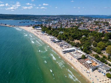 Yazın ortasında Bulgaristan 'ın hareketli Varna sahili ve gezinti alanının havadan görünüşü. Sahne canlı sahil yaşamını, berrak suları ve şehir manzarasını sergiliyor..