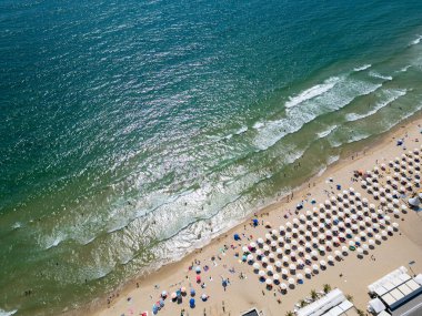 Yazın ortasında Bulgaristan 'ın hareketli Varna sahili ve gezinti alanının havadan görünüşü. Sahne canlı sahil yaşamını, berrak suları ve şehir manzarasını sergiliyor..