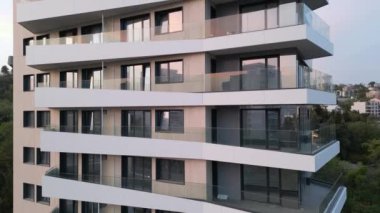 Bej paneller ve beyaz balkonlarla modern bir yerleşim alanının hava aracı görüntüsü, temiz mimari çizgiler ve çağdaş şehir tasarımı vurgulanıyor..