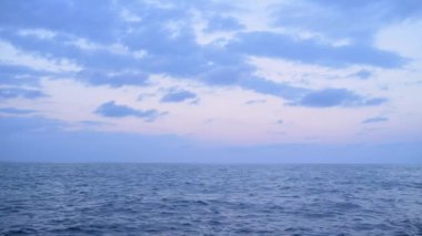 Alacakaranlıkta huzurlu bir okyanus manzarası, sakin sular ve yumuşak bulutlar Pastel gökyüzüne yayılmış. Sakin atmosfer, doğayla bir huzur ve bağlantı hissi uyandırıyor..