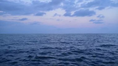 Alacakaranlıkta huzurlu bir okyanus manzarası, sakin sular ve yumuşak bulutlar Pastel gökyüzüne yayılmış. Sakin atmosfer, doğayla bir huzur ve bağlantı hissi uyandırıyor..
