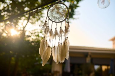 Güzelce hazırlanmış, tüylerle süslenmiş, rüzgarda hafifçe sallanan, batan güneşin yumuşak parıltısıyla aydınlatılan, dışarıda huzurlu bir atmosfer yaratan bir düş kapanı..