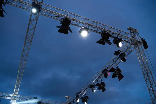 stock image The setup showcases multiple stage lights arranged on metal trusses, illuminating the sky as the evening sets in, readying for a vibrant outdoor performance.