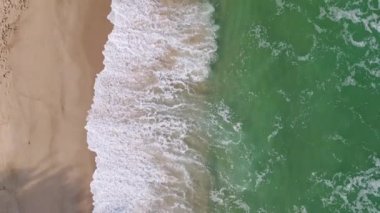 Yumuşak dalgalar, güneş ışığını yansıtan kumlu bir kıyıya taşar. Huzurlu sahil, kıyı şeridi boyunca sakin yürüyüşler yaparak huzurlu bir kaçış sunuyor..