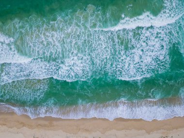 Yumuşak dalgalar, güneş ışığını yansıtan kumlu bir kıyıya taşar. Huzurlu sahil, kıyı şeridi boyunca sakin yürüyüşler yaparak huzurlu bir kaçış sunuyor..