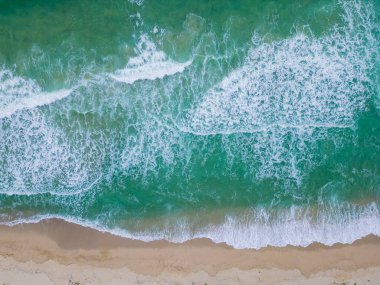 Yumuşak dalgalar, güneş ışığını yansıtan kumlu bir kıyıya taşar. Huzurlu sahil, kıyı şeridi boyunca sakin yürüyüşler yaparak huzurlu bir kaçış sunuyor..