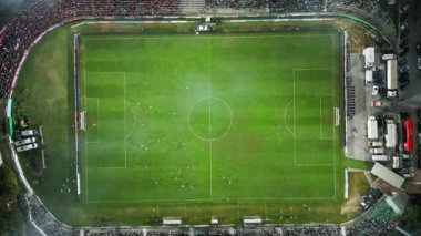 Yukarıdan aşağıya bir futbol maçının insansız hava aracı görüntüleri, kaleye yakın yoğun bir oyunda sahadaki oyuncuları gösteriyor ve benzersiz bir hava perspektifi sunuyor..