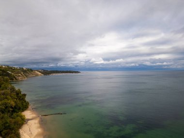 Sakin bir sahil manzarası kumlu bir sahil, yemyeşil uçurumlar, ve bulutlu bir gökyüzünün altında ufka uzanan sakin sular. Seyahat, doğa ya da kıyı teması için mükemmel. Varna, Bulgaristan.