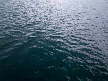 Dalgalanan koyu mavi deniz suyunun hava aracı görüntüsü. Dokulu yüzey, arka planlar, okyanus temaları ve doğa kavramları için mükemmel sakin, minimalist bir sahne yaratır..