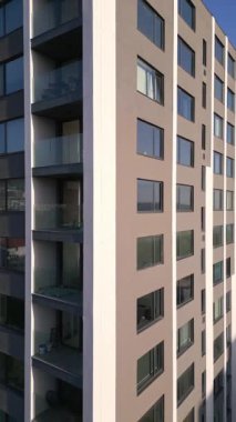 Pürüzsüz balkonları ve geniş pencereleri olan modern bir gökdeleni gösteren bir insansız hava aracı. Arka plandaki okyanus ve çevre yeşillik şehir-kıyı cazibesini artırıyor..