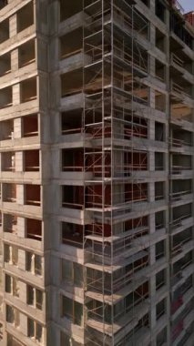Gün batımında gökdelen bir binanın inşaat alanını kaydeden bir drone videosu. Yapılar, beton iskelet, vinç ve iskele sıcak güneş ışığıyla yıkanarak kentsel gelişimi vurguluyor.
