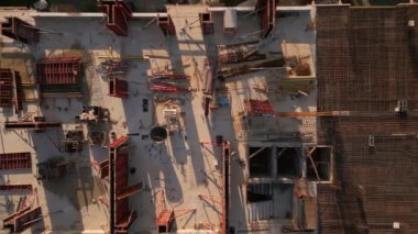 Bir inşaat alanının tepeden tırnağa görüntüsünü gösteren bir İHA videosu. Görüntü, mimari gelişimin ilk aşamalarını vurgulayarak binaların temellerini, iskelesini ve malzemelerini yakalıyor..
