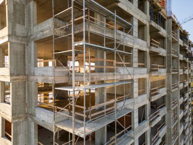 Gün batımında gökdelen bir binanın inşaat alanını kaydeden bir drone videosu. Yapılar, beton iskelet, vinç ve iskele sıcak güneş ışığıyla yıkanarak kentsel gelişimi vurguluyor.