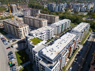 Yüksek konut binaları, renkli mimarisi ve otoparkları olan yoğun nüfuslu bir şehir bölgesinin havadan görüntüsü. Şehir manzarası, kalabalık bir mahallede modern yaşamı gözler önüne seriyor. İHA ile vurulmuş.