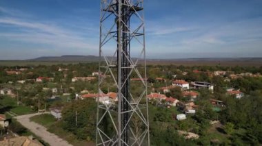 Köy ve arka planda tarlaları olan kırsal bir bölgedeki bir telekomünikasyon kulesine yakın çekim. İletişim teknolojisi doğal ortamla harmanlanır..