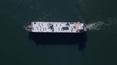 Sakin suda yüzen büyük bir kargo gemisinin yukarıdan aşağı görüntüsü. Güverte ve gemi yapısının net görünümü, deniz taşımacılığı ve lojistiği vurgulanıyor.