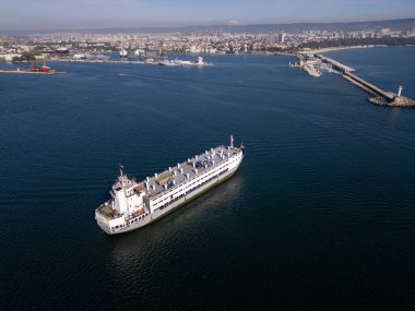 Sakin sularda seyreden büyük bir kargo gemisinin hava görüntüsü, deniz yüzeyine yansıyan güneş ışığı. Dinamik bir deniz sahnesi gemilerin yolculuğunu yakalıyor..