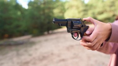 Atıştan sonra namludan dumanlar yükselirken atış poligonunda tabanca ateşleyen bir kişi. Eller sıkıca silahı kavrıyor, hareket anını yakalıyor..