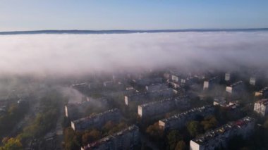 Bulgaristan 'ın Varna kentinin insansız hava aracı görüntüsü, kısmen görünür apartmanlarla kaplı sabah sisi ile kaplı şehir manzarası, sisli ve yumuşak ışığa batmış sakin bir kent manzarasını yakalıyor.