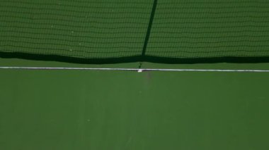 Pickleball sahalarının tepeden tırnağa mavi ve yeşil renkli, geometrik çizgileri ve net gölgeleri gösteren, spor, eğlence ve soyut görsel temalar için ideal hava aracı görüntüsü..