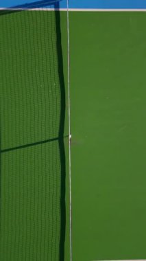 Pickleball sahalarının tepeden tırnağa mavi ve yeşil renkli, geometrik çizgileri ve net gölgeleri gösteren, spor, eğlence ve soyut görsel temalar için ideal hava aracı görüntüsü..