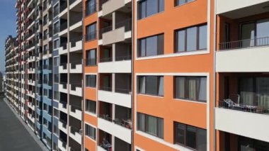 Balkonları ve geometrik cephe tasarımı olan renkli konut binalarının hava aracı görüntüsü, modern kentsel mimari ve canlı dış detayları şehir ortamında sergiliyor..