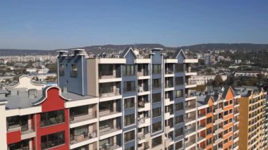 Balkonları ve geometrik cephe tasarımı olan renkli konut binalarının hava aracı görüntüsü, modern kentsel mimari ve canlı dış detayları şehir ortamında sergiliyor..