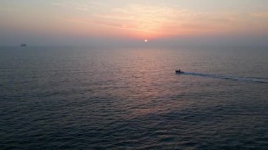 Gün batımında sakin bir denizin, yumuşak dalgalar ve ufukta süzülen ılık bir güneşin, rahatlatıcı ve pitoresk bir okyanus manzarası yaratarak, rahatlatıcı temalar için ideal bir hava aracı görüntüsü..