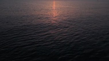 Gün batımında sakin bir denizin, yumuşak dalgalar ve ufukta süzülen ılık bir güneşin, rahatlatıcı ve pitoresk bir okyanus manzarası yaratarak, rahatlatıcı temalar için ideal bir hava aracı görüntüsü..