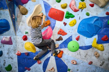 6 yaşında bir çocuk canlı bir kayanın üzerine tırmanıyor ve rengarenk duvarlara tırmanıyor, eğlenceli ve aktif bir tırmanış deneyimi yaşıyor. Çocuklar için spor ve macera için mükemmel..