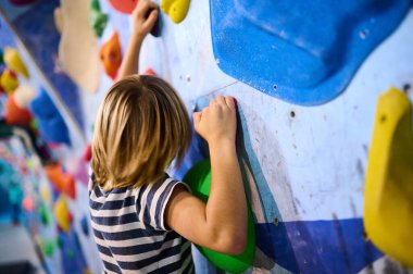 6 yaşında bir çocuk canlı bir kayanın üzerine tırmanıyor ve rengarenk duvarlara tırmanıyor, eğlenceli ve aktif bir tırmanış deneyimi yaşıyor. Çocuklar için spor ve macera için mükemmel..