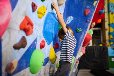 6 yaşında bir çocuk canlı bir kayanın üzerine tırmanıyor ve rengarenk duvarlara tırmanıyor, eğlenceli ve aktif bir tırmanış deneyimi yaşıyor. Çocuklar için spor ve macera için mükemmel..