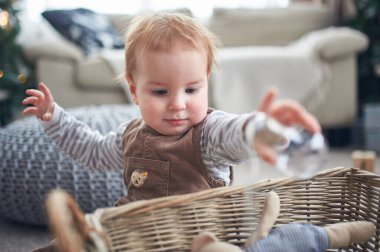 Genç bir çocuk parlak ve rahat bir oturma odasında oyuncakları keşfeder. Yumuşak mobilyalarla çevrili küçük çocuk, merakını ve neşesini gösteren küçük bir nesneye uzanıyor..