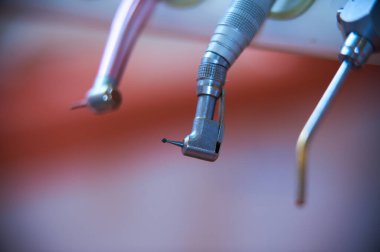 Temiz bir klinikte kullanılmak üzere hazırlanmış diş aletlerinin ayrıntılı görünümü. Işığı yansıtan araçlar, diş muayenesine veya tedaviye hazır olduğunu gösterir.