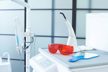 Parlak diş sağlığı kliniğinde diş lazeri, koruyucu gözlük ve yansıtıcı bir yüzey gibi bir dizi alet bulunur. Hepsi de randevular sırasında etkin hasta bakımı için düzenlenmiştir..