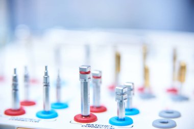 Beyaz bir yüzeye diş implantı cerrahisi aletleri. Bir tıbbi veya diş kliniğinde altın matkap uçları ve hassas aletlerin yakın plan çekimi