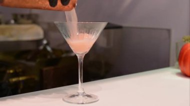 Bakır karıştırıcıdan martini bardağına bir kokteyl dökmek, profesyonel bir ortamda bar hazırlamak zarif bir cam ve pürüzsüz bir infaz..