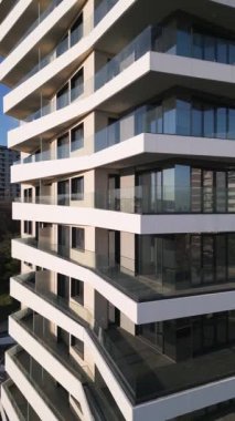 Çağdaş bir konut yapısı, kıvrımlı balkonları ve geniş pencereleri olan kendine özgü bir fa ade ile ayakta duruyor. Güneş ışığı parlak gökyüzüne karşı parlak mimariyi aydınlatır..