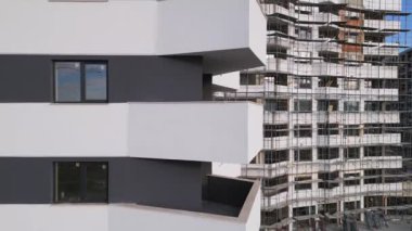 Çarpıcı bir bakış açısı, kısmen tamamlanmış bir yapıya karşı yan yana gelen yeni bir binanın modern mimari tasarımını vurguluyor. Sahne, şehir siluetinde bir tarz karışımını yakalar..