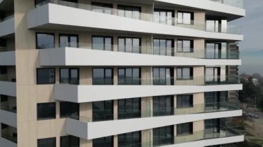 Çağdaş bir apartmanda birden fazla balkonu olan çarpıcı bir cephe sergileniyor. Tasarım, şehir manzarasında eşsiz bir estetik sunan temiz çizgiler ve çeşitli seviyelere sahiptir..