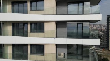 Bu çağdaş apartmanda geniş cam balkonlu parlak tasarım unsurları sergileniyor. Kentsel bir ortamda yer alan bina, çevredeki manzaranın çarpıcı görüntülerini sunuyor..