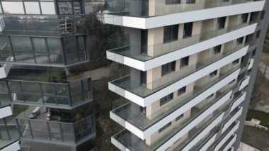Gösterişli ve modern bir apartmanda birden fazla kat ve balkon bulunur. Tasarım, kalabalık bir şehirde davetkar bir atmosfer yaratarak büyük cam pencereler sergiliyor..