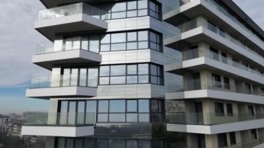 Gösterişli, modern konut binasında birden fazla cam balkon ve büyük pencereler yer alıyor. Çağdaş mimariyle şehir manzarasını berrak bir gökyüzünün altında harmanlıyor..