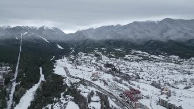 Sakin bir kış manzarası karla kaplı dağları ve dolambaçlı bir nehri gözler önüne seriyor. Sahne, kışın dingin güzelliğini vurgulayarak doğanın ortasına yerleşmiş bir tatil köyü yakalıyor. Bansko, Bulgaristan