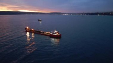 Sakin sularda gün batımında parlak bir tanker gemisi, canlı renkler ve sakin bir deniz atmosferi. Nakliye, ticaret ve okyanus taşımacılığı konuları için mükemmel