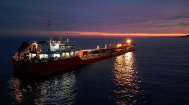Sakin sularda gün batımında parlak bir tanker gemisi, canlı renkler ve sakin bir deniz atmosferi. Nakliye, ticaret ve okyanus taşımacılığı konuları için mükemmel